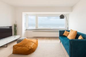 a living room with a blue couch and a window at Prachtig Zeezicht Appartement in Ostend