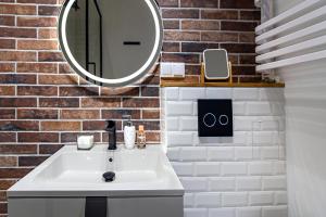 ein Badezimmer mit einem weißen Waschbecken und einem Spiegel in der Unterkunft Hillside7 Micro-Loft in Bielsko-Biała