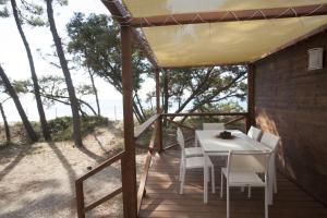 a table and chairs on a deck with a view of the beach at PuntAla Camp & Resort in Punta Ala
