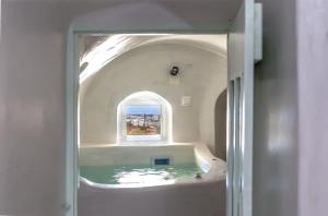 a bathroom with a bath tub with a window at Exi Castle Suites in Emporio Santorini