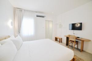 a bedroom with a bed and a desk and a television at Evergreen Cafe and Hotel in Chiang Mai
