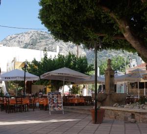 an outdoor cafe with tables and umbrellas and chairs at Lotza Traditional House Salakos in Sálakos +21 photos