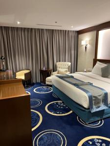 Swiss In Tabuk Hotel في تبوك: غرفة فندقية بسرير كبير وكرسي