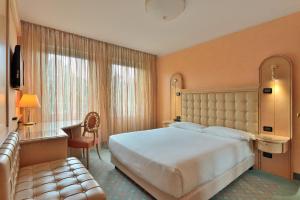ein Hotelzimmer mit einem großen Bett und einem Sofa in der Unterkunft Agora' Palace Hotel in Biella