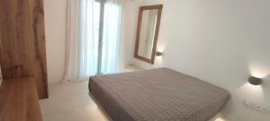 a bedroom with a bed and a mirror and a window at Degaetas Resort in Antiparos