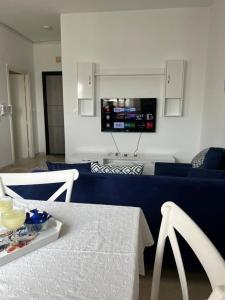 a living room with a blue couch and a tv on the wall at Residence Mariem in Ariana