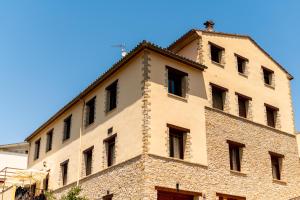 un gran edificio de ladrillo con ventanas en la parte superior en Hostal El Guerrer, en Todolella (Tolella)