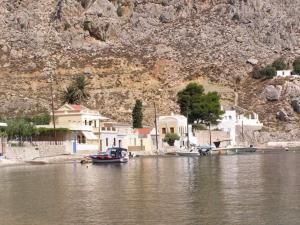 a boat in a body of water next to houses at Symi . VILLA CALME (Sur la Mer). in Symi