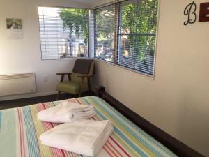 a room with two beds and a chair and a window at Stay in School by the Sea in Dunedin