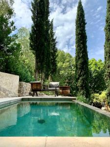 einen Pool in einem Garten mit einer Bank und Bäumen in der Unterkunft La Bouscatière in Moustiers-Sainte-Marie