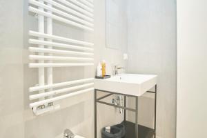 La salle de bains blanche est pourvue d'un lavabo et d'un miroir. dans l'établissement Casa Contra, à La Spezia