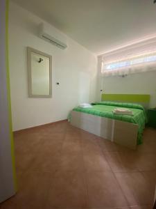 ein Schlafzimmer mit einem grünen Bett und einem Spiegel in der Unterkunft Santa Marina Inn in Milazzo