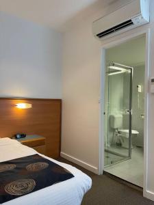 a bedroom with a bed and a bathroom with a toilet at 435/247 gouger st. ex hotel room in the city in Adelaide