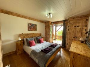 Chalet Le Doux Si, Large Self-Contained Apartment, 2km from Doucy-Combelouvière and close to Valmorel في La Lechere: غرفة نوم بسرير ومخدات حمراء