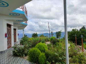 a garden in front of a building with flowers at Kasar wonder hill homestay in Almora