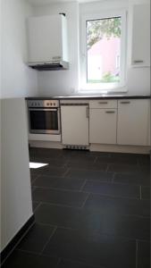una cucina con armadietti bianchi e pavimento piastrellato nero di Felseck Zimmer a Innsbruck Altre 19 foto