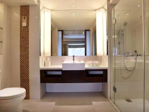 a bathroom with a sink and a toilet and a shower at Novotel Lombok Resort & Villas in Kuta Lombok