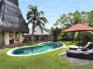 a resort with a swimming pool and an umbrella at Novotel Lombok Resort & Villas in Kuta Lombok