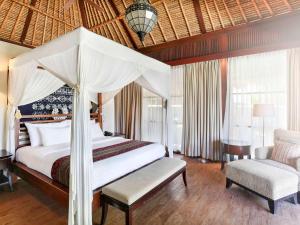 a bedroom with a large bed and a chair at Novotel Lombok Resort & Villas in Kuta Lombok