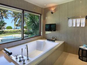 a large white tub in a bathroom with a window at Novotel Lombok Resort & Villas in Kuta Lombok