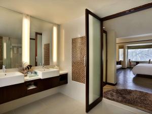 a bathroom with two sinks and a bedroom at Novotel Lombok Resort & Villas in Kuta Lombok
