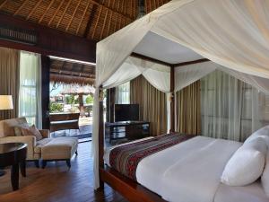 a bedroom with a canopy bed and a living room at Novotel Lombok Resort & Villas in Kuta Lombok