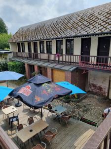 a patio with tables and umbrellas on a deck at hotel du commerce in Fauville-en-Caux