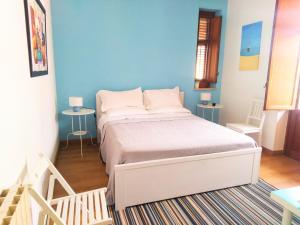 a bedroom with a white bed and a blue wall at Garden House Alla Torre in Isola delle Femmine