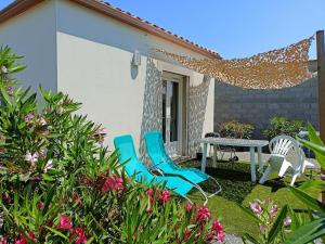 a patio with two blue chairs and a table at Le Logis de Liliana in Villemoustaussou