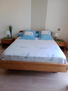 sypialnia z drewnianym łóżkiem z niebieskimi poduszkami w obiekcie Chambre d'hôtes le Berceau w mieście Meschers-sur-Gironde