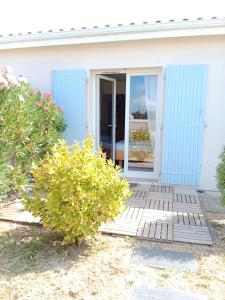 een wit huis met een blauwe deur en een struik bij Chambre d'hôtes le Berceau in Meschers-sur-Gironde