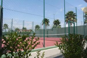 um campo de ténis com palmeiras e uma cerca em Isla Canela Apartamento nuevo en primera línea de playa con vistas al mar em Isla Canela