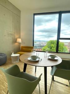einen Tisch und Stühle in einem Zimmer mit einem großen Fenster in der Unterkunft CAMPUS CARRÉE - Modernes und zentrales Apartment in Kassel in Kassel