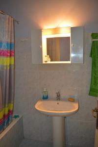 uma casa de banho com um lavatório e um espelho em Mauve Apartment em Argostólion