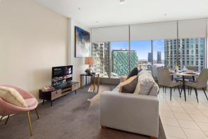 a living room with a couch and a tv and a table at Sophisticated Designer Condo W River & City Views in Melbourne