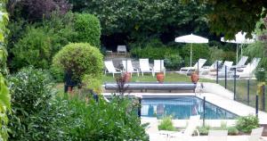 - une piscine avec des chaises et un parasol dans le jardin dans l'établissement Logis Hôtel La Tonnellerie, à Beaugency