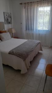 a bedroom with a large white bed with a window at A Apartmento Solar dos Pinheiros in Vilamoura