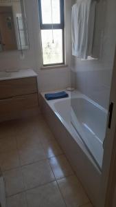 a white bathroom with a tub and a window at A Apartmento Solar dos Pinheiros in Vilamoura +8 photos