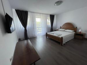 a bedroom with a bed and a large window at Cazare Vila Maria in Curtea de Argeş