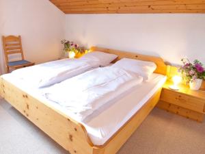 ein großes Holzbett in einem Zimmer mit Stuhl in der Unterkunft Landhaus am Breitenberg in Pfronten