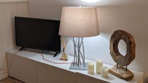 een tafel met een televisie en een lamp en kaarsen bij Seashore Hideaway studio in Hermanville-sur-Mer