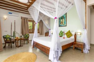 a bedroom with a bed with a mosquito net at Zanzibar Queen Hotel in Matemwe