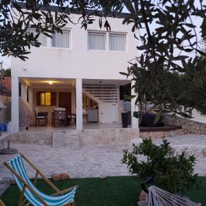 a house with two lawn chairs in front of it at Bijela kuča in Mali Drvenik