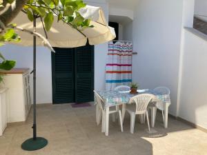 カストロ・ディ・レッチェにあるCasa Vacanza "Castro Marina"のテーブルと椅子、傘が備わります。