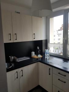 uma cozinha com armários brancos e um balcão preto em Apartament Przy Ratuszu em Malbork