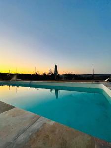 una piscina blu con il tramonto sullo sfondo di Posada Matadero a Cortelazor Altre 21 foto