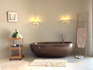 een groot bruin bad in een badkamer met 2 verlichting bij Casa de l’Albada in Roses