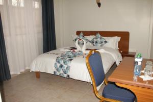 um quarto com uma cama, uma secretária e uma cadeira em Sai Inn Eldoret em Eldoret