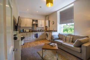 a living room with a couch and a kitchen at Astor House in Torquay