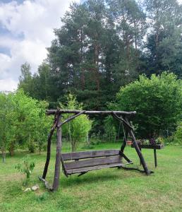 drewniana huśtawka siedząca na trawiastym polu w obiekcie Wynajem pokoi WIKI w mieście Mikołajki